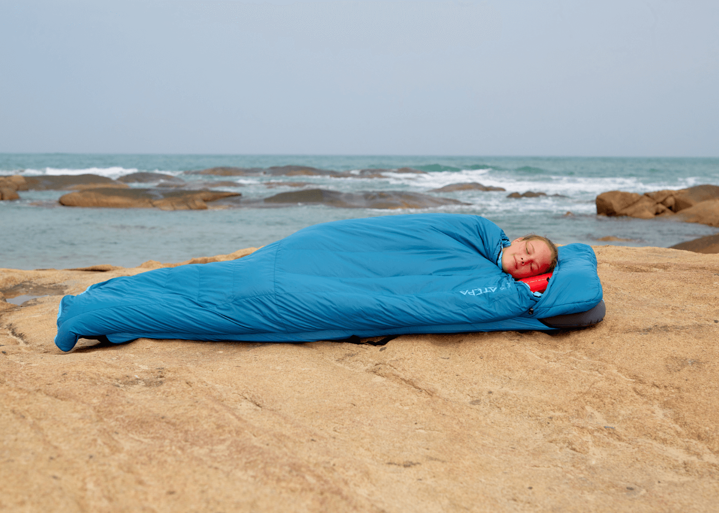 Down sleeping bag displayed on grass for camping and hiking activities